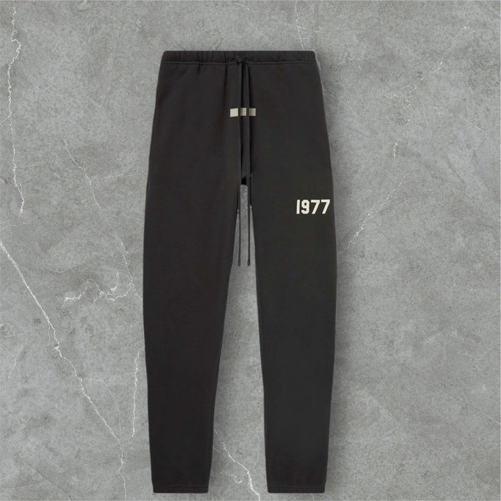 Fear of God Essentials sweatpants featuring a minimalist design with the year 1977 printed on them.