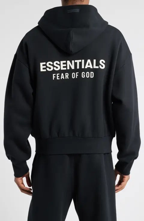 Fear of God FOG Essentials hoodie showcasing the back view with white lettering on a black fabric.