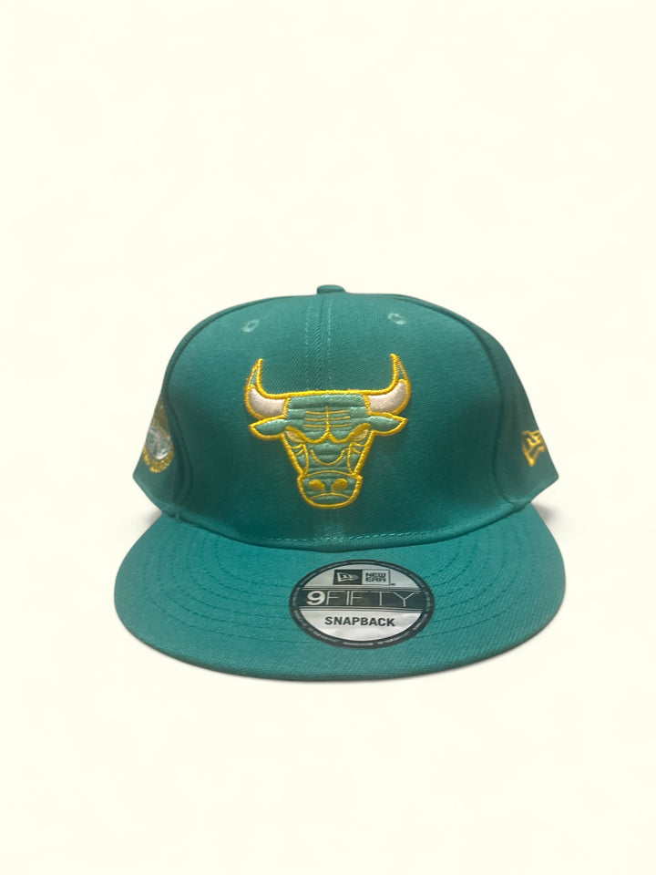 Chicago Bulls fitted cap in teal with golden embroidery, showcasing the iconic Bulls logo.